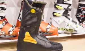 Czarne buty narciarskie podgrzewane z pomarańczowymi akcentami, gotowe na zimowe szaleństwo.