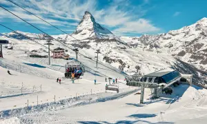 Widok na góry i stoki narciarskie z kolejką linową. Widać znaki na stokach narciarskich, narciarzy i snowboardzistów.