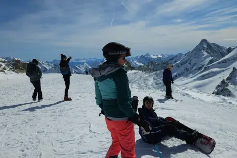 Sztruks na stoku. Grupa narciarzy i snowboardzistów podziwia alpejskie krajobrazy.
