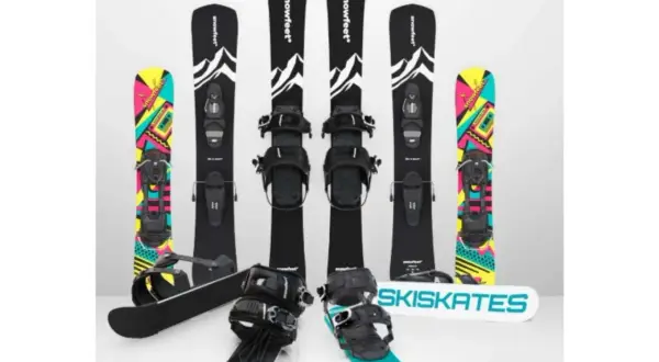 Narty do skakania i snowboardy z kolorowymi grafikami. Dwa zestawy nart do skakania z czarnymi wiązaniami i grafiką górską. Dwa snowboardy z kolorowymi wzorami.
