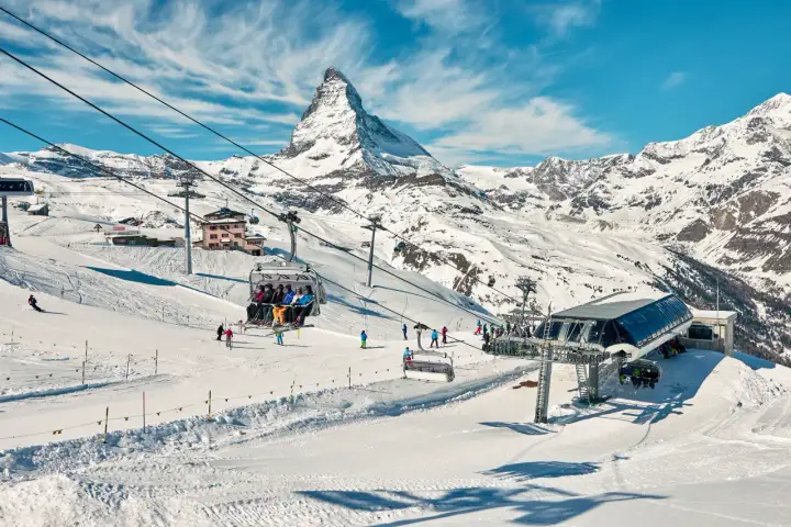 Widok na góry i stoki narciarskie z kolejką linową. Widać znaki na stokach narciarskich, narciarzy i snowboardzistów.